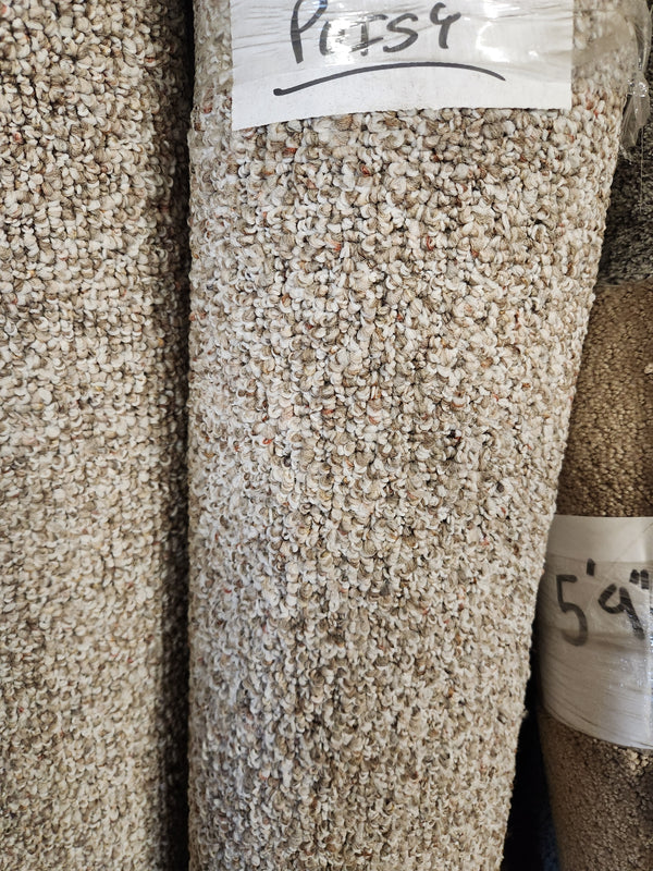 A close-up of a rolled Carpet Remnant 5' X 8' by Flooring CLEARANCE with a textured beige surface and label on top.