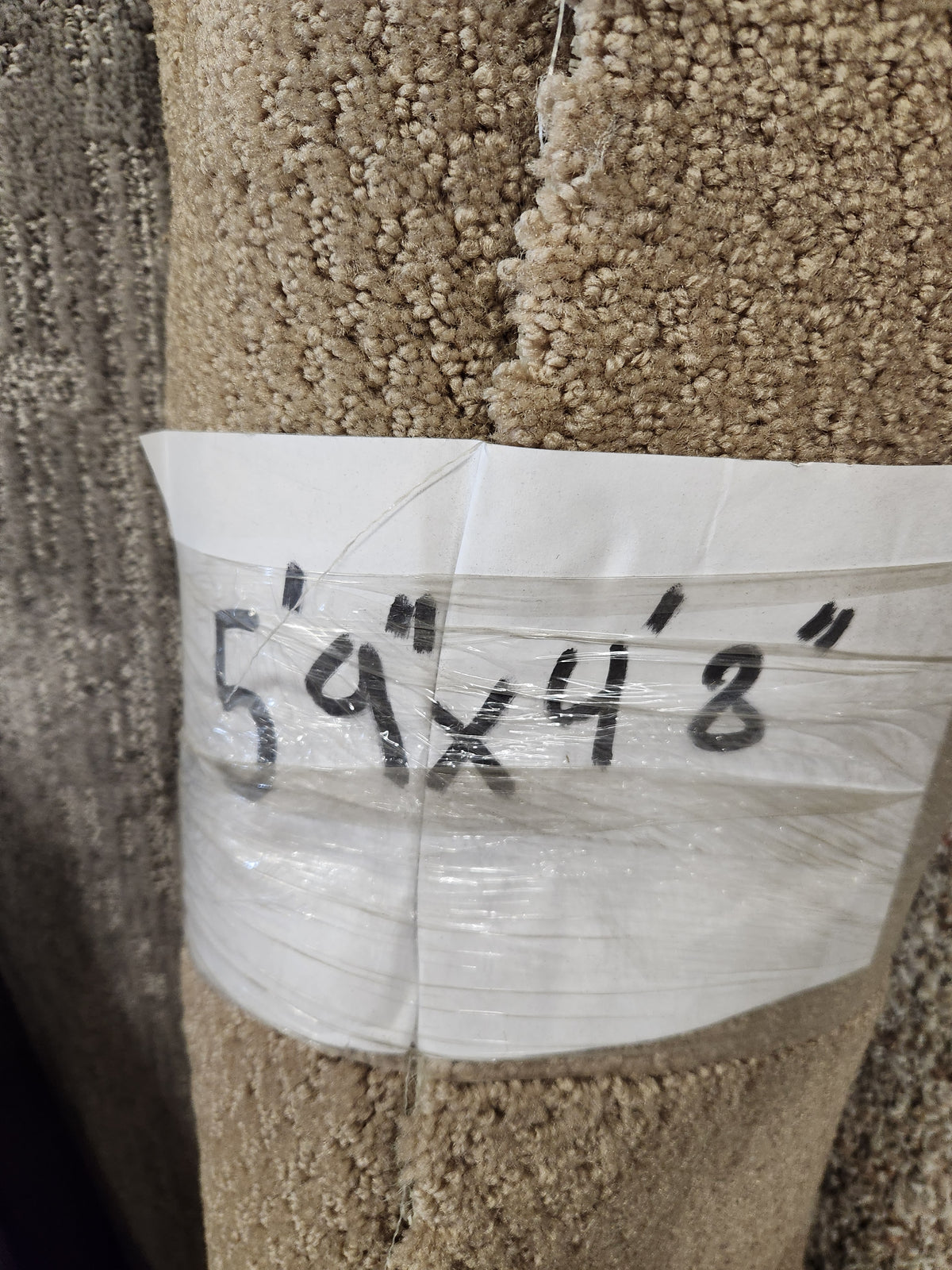 A Flooring CLEARANCE label on a medium pile Carpet Remnant 5'9" X 4'8" is marked in black.