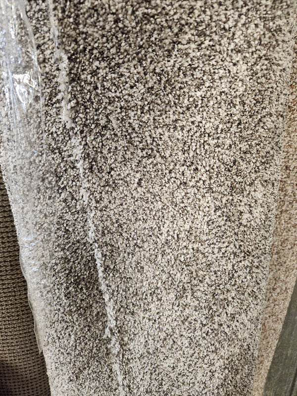A Flooring CLEARANCE Carpet Remnant 12' X 5'4", dark grey/white speckled, rolled and partially wrapped in plastic.