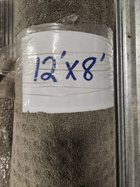 A rolled-up Flooring CLEARANCE Carpet Remnant 12' X 8', beige, low pile, wrapped in plastic with a handwritten sign.