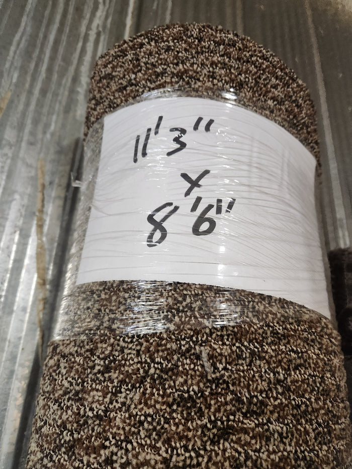 A brown patterned medium pile Carpet Remnant 11'3" x 8'6" by Flooring CLEARANCE, rolled and wrapped in plastic.