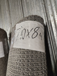 A Flooring CLEARANCE Carpet Remnant 7'10" x 8'4" in light grey leans against a corrugated metal wall.