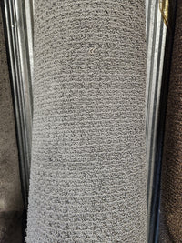 A close-up of a Flooring CLEARANCE Carpet Remnant 7'10" X 8'4" in Low Loop Pile light grey against a metal background.