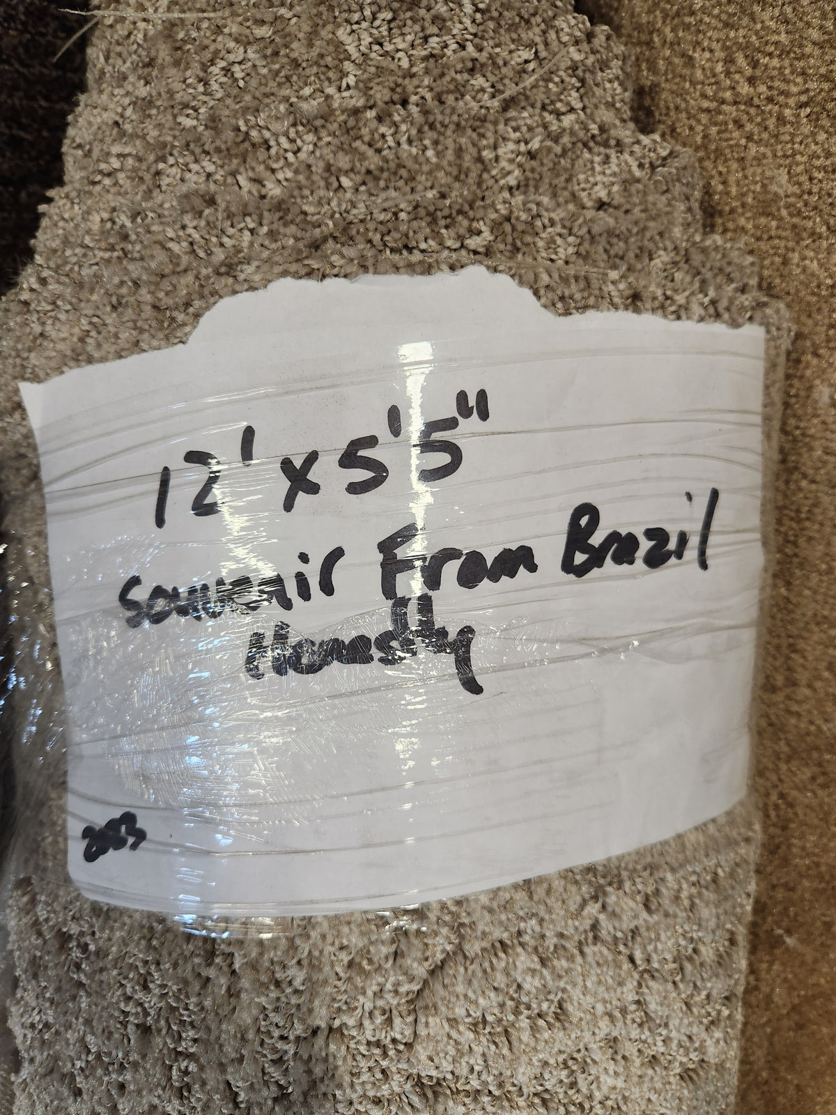 A light beige, medium pile Flooring CLEARANCE Carpet Remnant 12' X 5'5" with handwritten label.