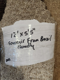 A light beige, medium pile Flooring CLEARANCE Carpet Remnant 12' X 5'5" with handwritten label.