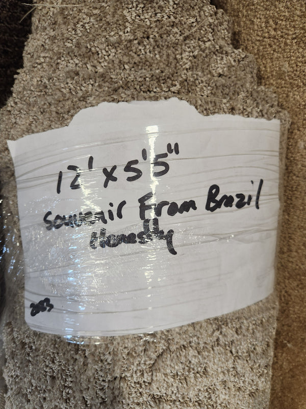 A light beige, medium pile Flooring CLEARANCE Carpet Remnant 12' X 5'5" with handwritten label.
