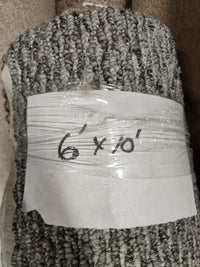 A Flooring CLEARANCE Carpet Remnant 6' x 10', low loop pile grey, wrapped in plastic with handwritten label.
