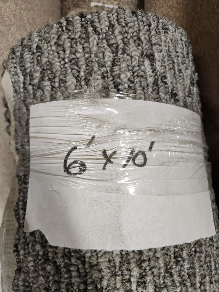 A Flooring CLEARANCE Carpet Remnant 6' x 10', low loop pile grey, wrapped in plastic with handwritten label.