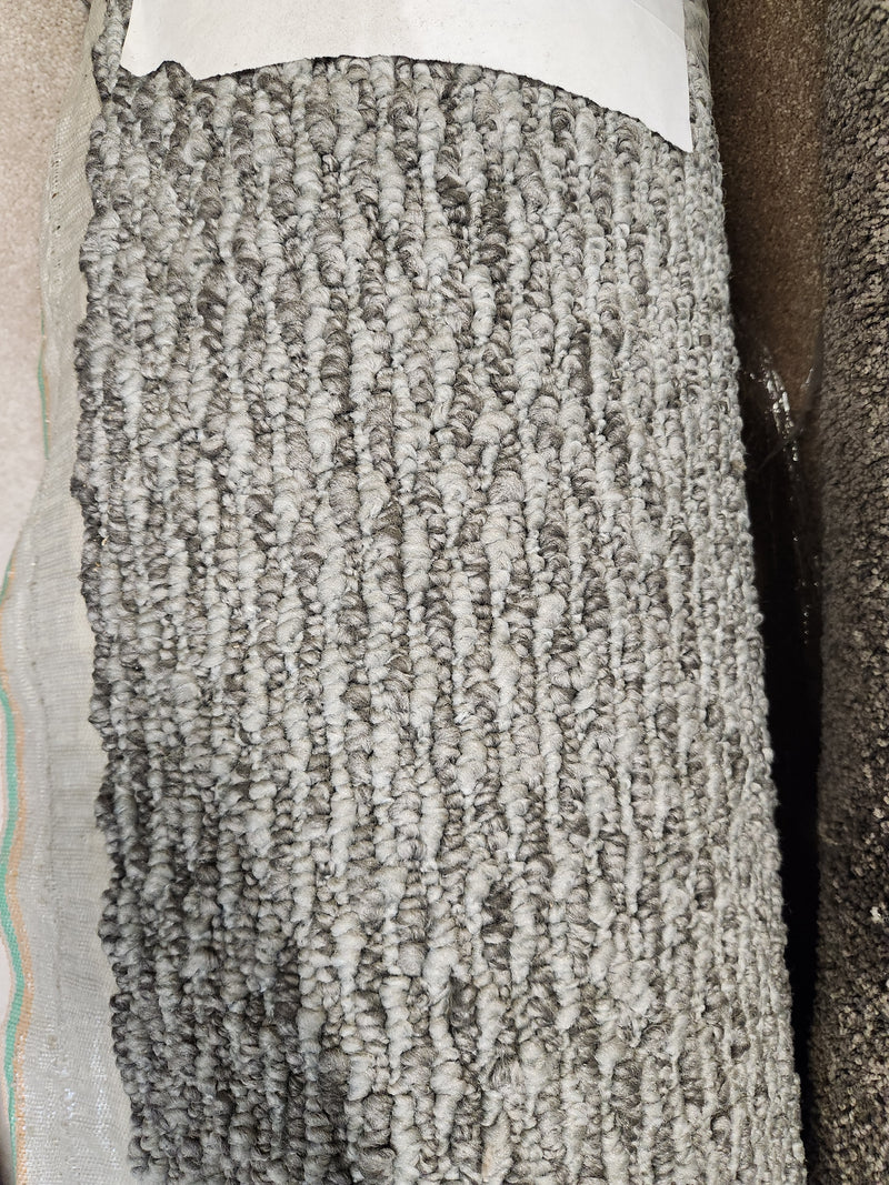 Close-up of Flooring CLEARANCE Carpet Remnant 6' X 10', low loop pile grey with textured fibers and partial white label.
