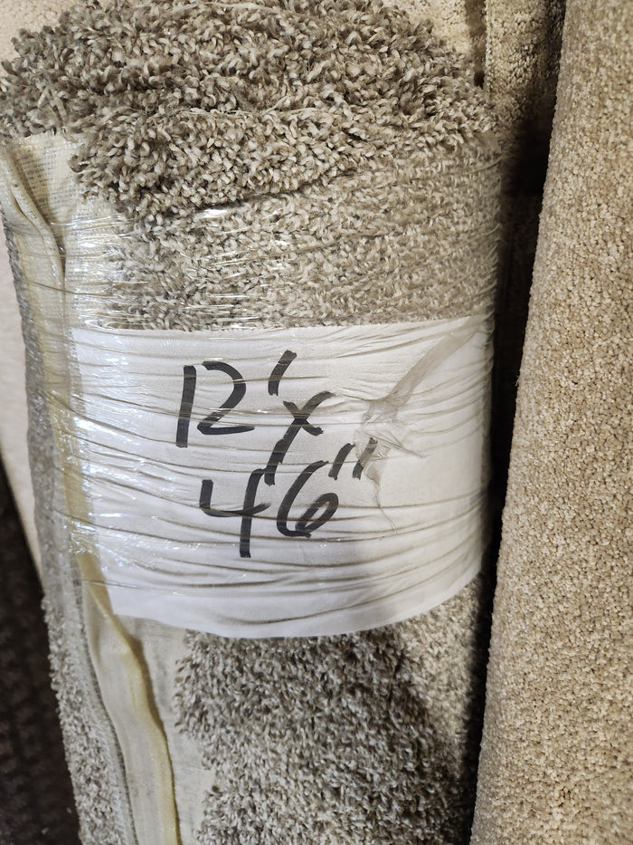 A Flooring CLEARANCE Carpet Remnant 12' x 4'6" in beige, medium pile is shown wrapped in plastic.