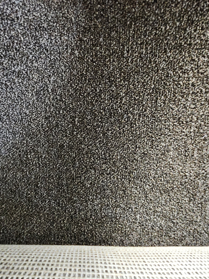 Close-up of Flooring CLEARANCE Carpet Remnant 3'7" X 22'6", medium pile brown with a light woven fabric strip.