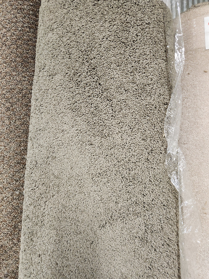 Several Flooring CLEARANCE Carpet Remnant 12' X 7'6" rolls in neutral tones stand upright, one partly wrapped.