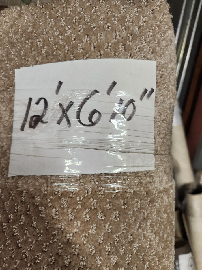 A handwritten label reads "Carpet Remnant 12' X 6'10"" by Flooring CLEARANCE on a beige, low pile rug roll.
