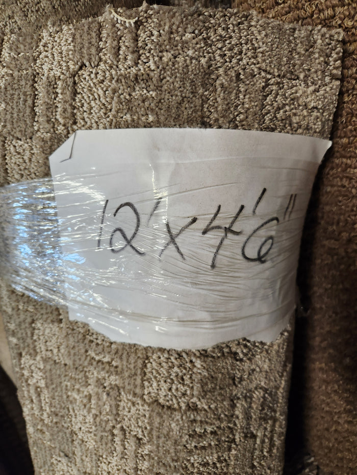 A Flooring CLEARANCE Carpet Remnant, 12" X 4'6", beige medium pile, is wrapped in plastic with a handwritten sign.