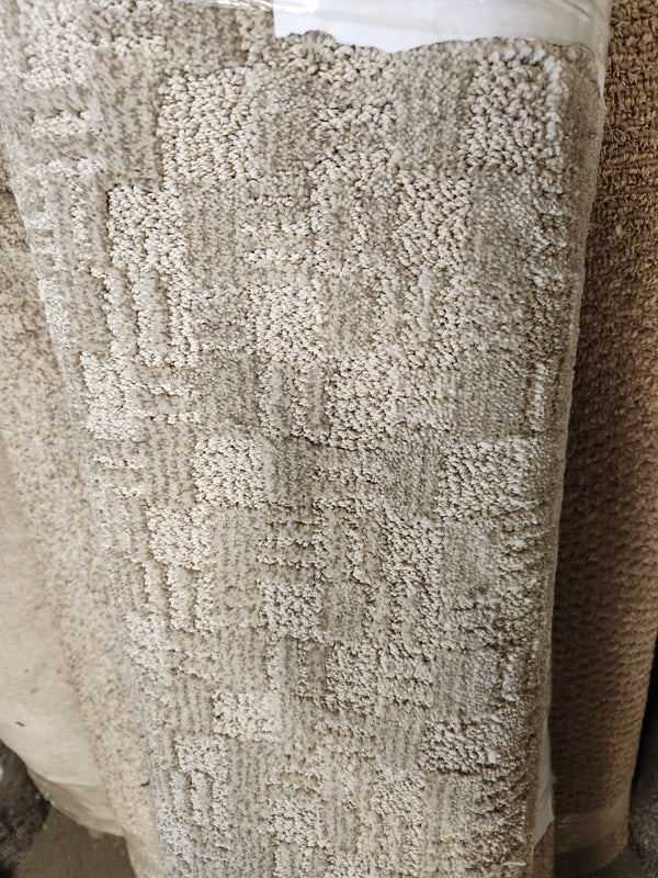 A 12" x 4'6" beige textured medium pile Carpet Remnant by Flooring CLEARANCE with a subtle square pattern.
