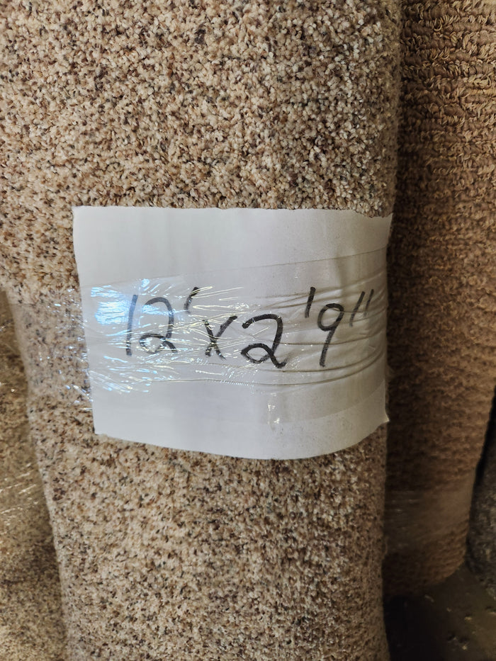 A Flooring CLEARANCE Carpet Remnant 12' X 2'9" in Multi Tan, high pile, rolled with a size label.