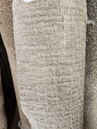 A close-up of Flooring CLEARANCE Carpet Remnant 8'6" X 9'4", tan grid-pattern, stacked with other rolls.