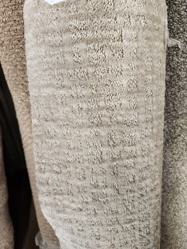 A close-up of Flooring CLEARANCE Carpet Remnant 8'6" X 9'4", tan grid-pattern, stacked with other rolls.