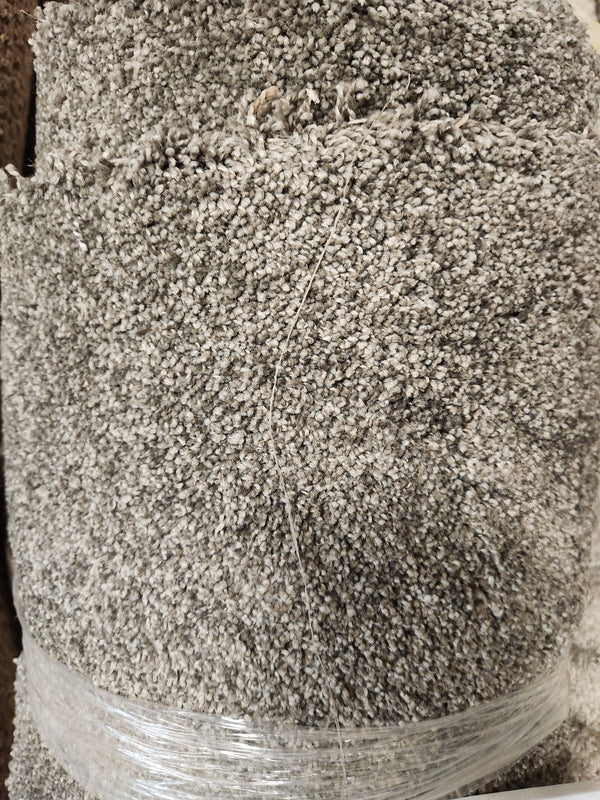 A close-up of Flooring CLEARANCE Carpet Remnant 12' X 5', dark grey, rolled and wrapped in clear plastic.