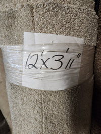 A Flooring CLEARANCE Carpet Remnant 12' x 3'11", grey, rolled and wrapped in plastic with a handwritten sign.
