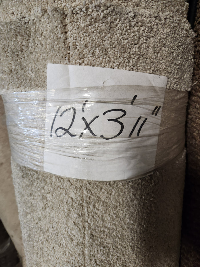 A Flooring CLEARANCE Carpet Remnant 12' x 3'11", grey, rolled and wrapped in plastic with a handwritten sign.