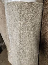 A large roll of Flooring CLEARANCE Carpet Remnant 12' X 3'11" stands upright in a warehouse setting.