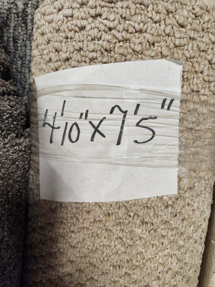 A rolled beige Carpet Remnant 4'10" X 7'5" by Flooring CLEARANCE with handwritten label on taped paper.