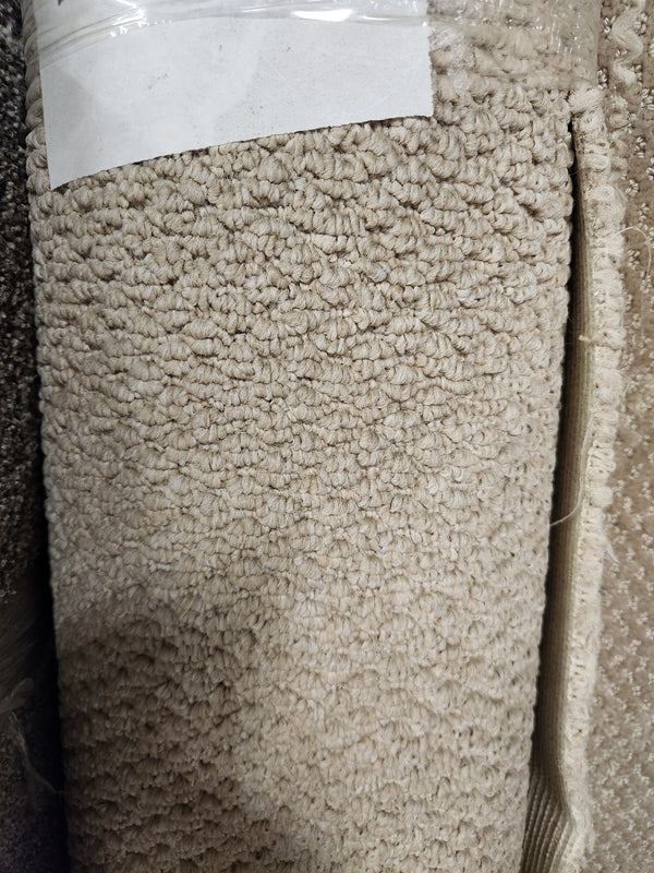 Close-up of Flooring CLEARANCE Carpet Remnant 4'10" X 7'5", looped beige roll with blank white label on top.