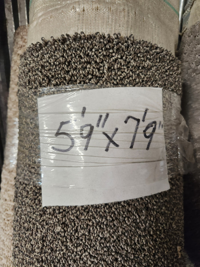 A Flooring CLEARANCE Carpet Remnant 5'9" x 7'9", Oreo pattern, wrapped in clear plastic with handwritten label.