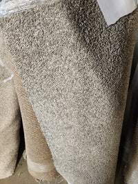 A close-up of Flooring CLEARANCE Carpet Remnant 13'9" X 3'6" with a textured grey surface, partially in plastic.