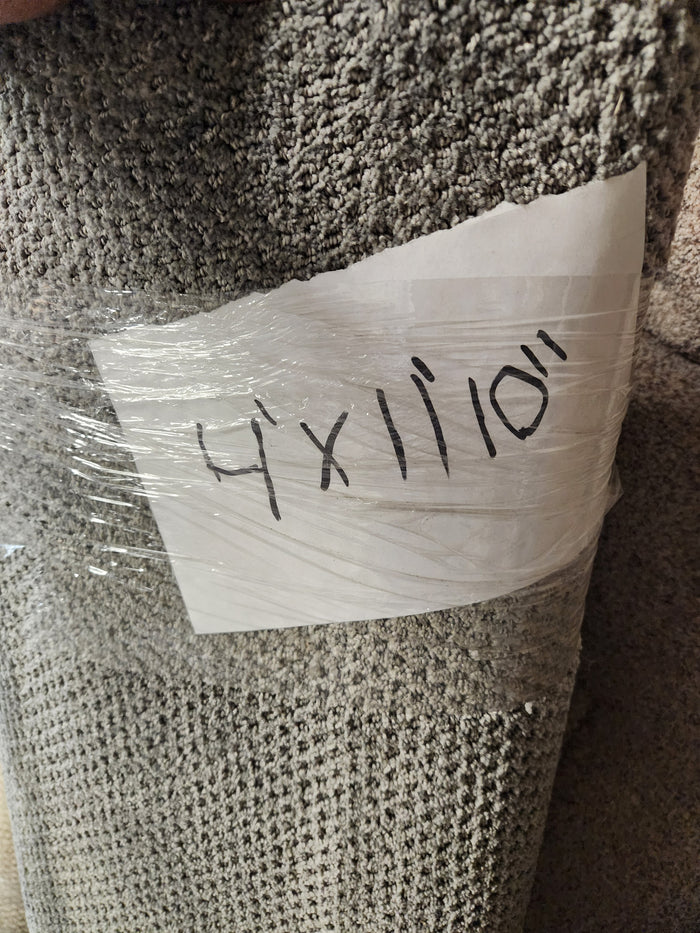 A rolled-up grey Flooring CLEARANCE Carpet Remnant 4' X 11" 10', wrapped in plastic with handwritten text.