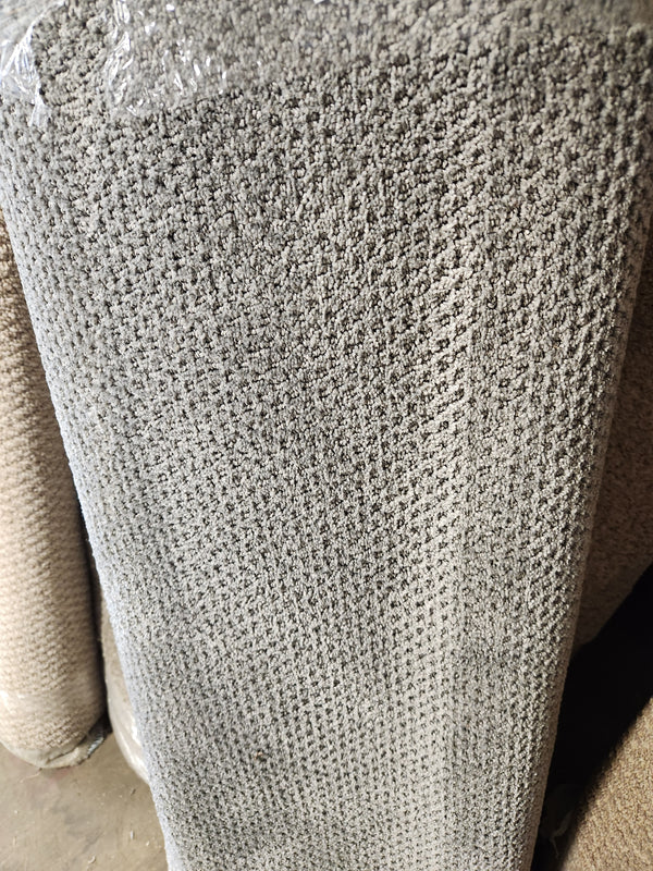 A close-up of the Flooring CLEARANCE Carpet Remnant 4' X 11" 10' in grey, rolled on a concrete floor.