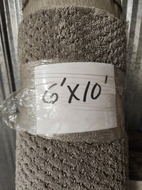 A Carpet Remnant 6' X 10' by Flooring CLEARANCE, beige with a looped pattern, rolled and wrapped in plastic.
