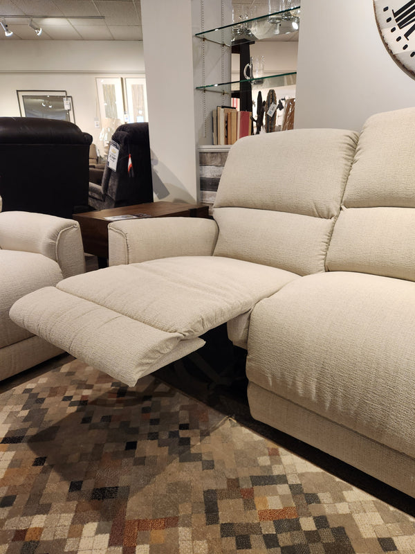 The La-Z-Boy 803 Cade Manual Reclining Sofa in beige, footrest extended, on a patterned rug in a showroom.
