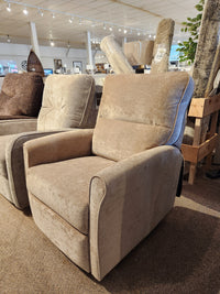 The Palliser Pinecrest Rocker Recliner, a beige upholstered chair with rolled arms, shown in a stylish showroom setting.