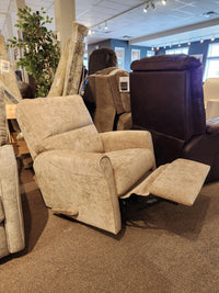 The Pinecrest Rocker Recliner by Palliser features beige upholstery, rolled arms, and an extended footrest—ideal for showrooms.