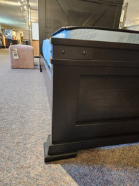 A Handstone Chattanooga Queen Bed with a blue mattress sits on carpet in a showroom.