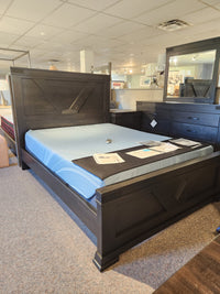 A Handstone Chattanooga Queen Bed in Heritage Maple Charcoal with a blue mattress is on display in the showroom.