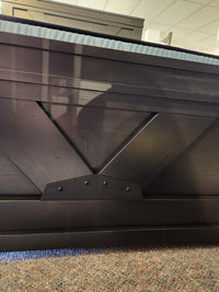 Close-up of a Handstone Chattanooga Queen Bed with custom metal hardware, set on a mottled carpeted floor.