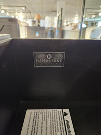 A metal "Handstone Crafted for Life" label is inside a Chattanooga 5 Drawer Highboy in a showroom.