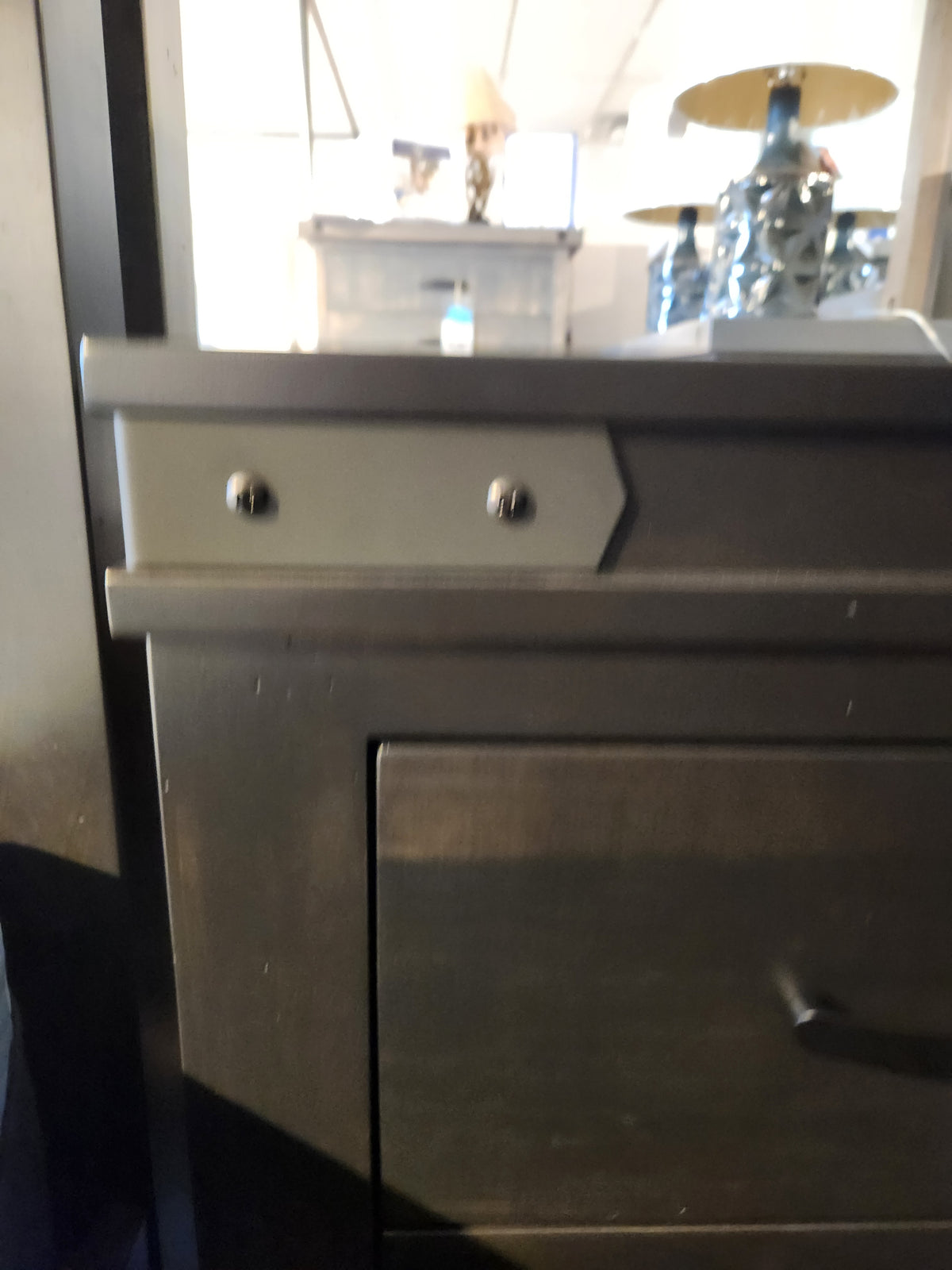 Close-up of a Handstone Chattanooga Power Nightstand with custom metal hardware, lamps, and furniture in the background.