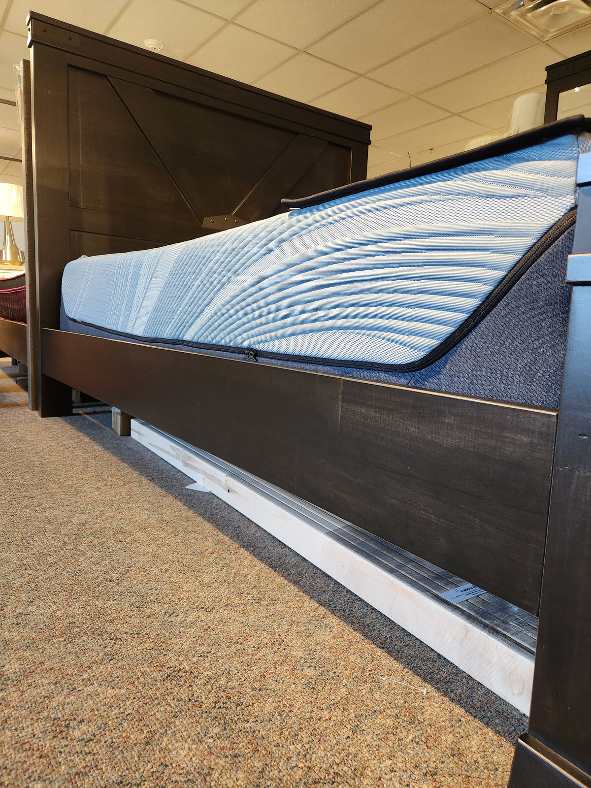 The Handstone Chattanooga Queen Bed in black wood with custom metal hardware and blue mattress, shown in a carpeted showroom.