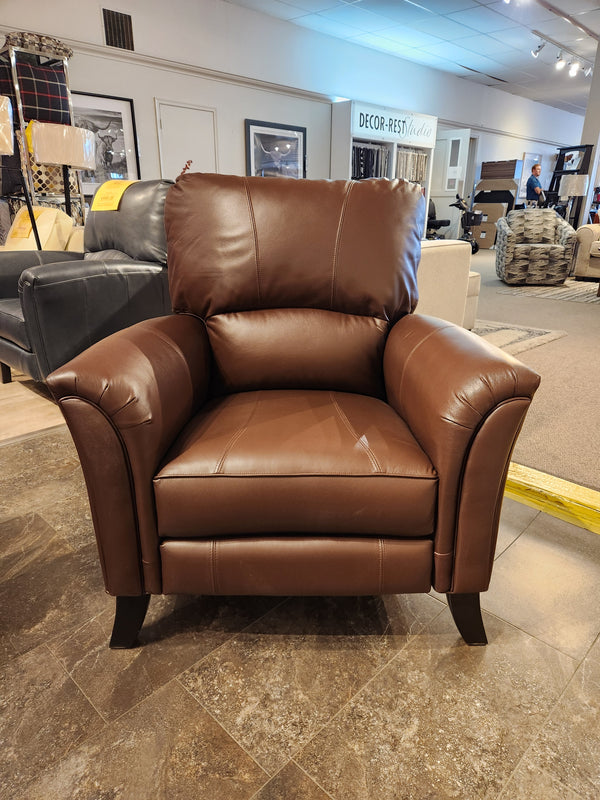 The Decor-rest 3450 Push Back Recliner, featuring wide arms and brown leather, is displayed in a furniture showroom.