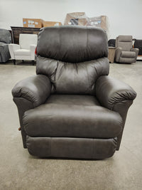 A dark brown La-Z-Boy 528 Larson All Leather Rocker Recliner with a chaise seat sits in a showroom with other chairs.