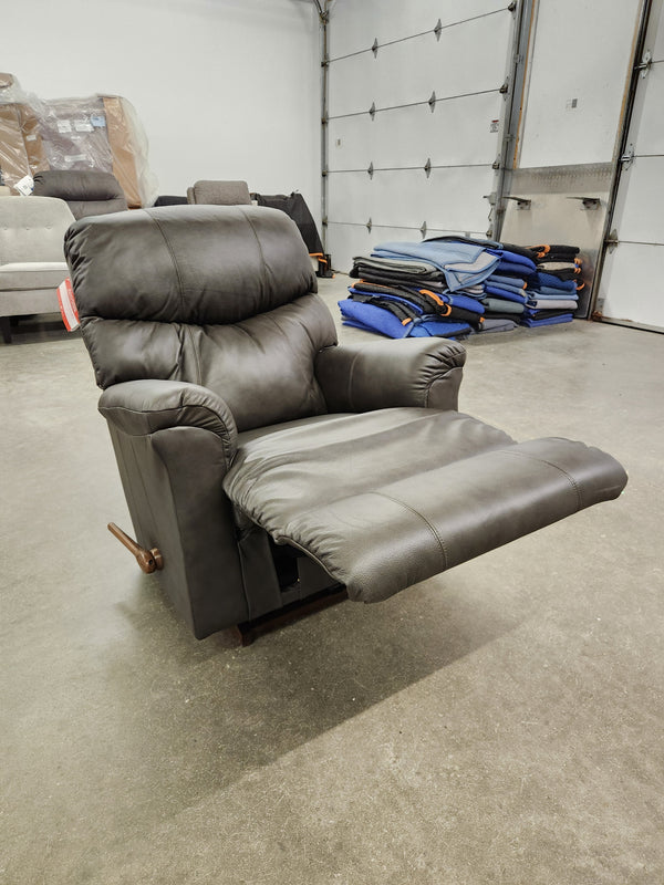 A dark gray La-Z-Boy 528 Larson All Leather Rocker Recliner with chaise seat and extended footrest in a warehouse.
