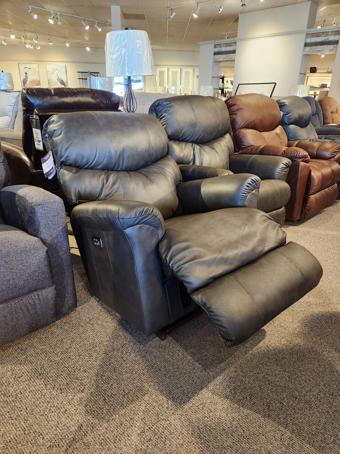 A black La-Z-Boy 528 Larson All Leather Power Rocker Recliner is shown in a showroom with other chairs.