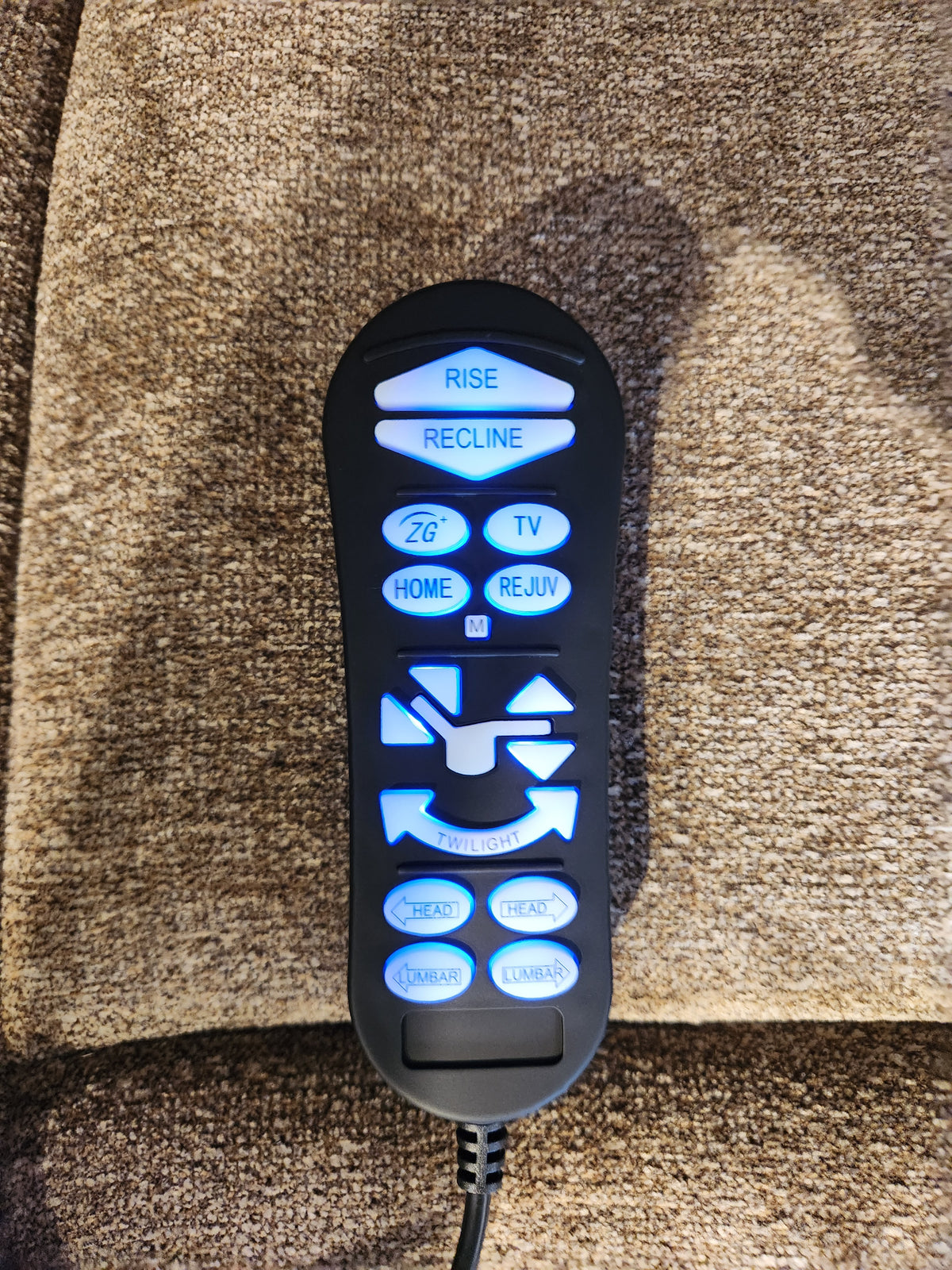 Remote control for Golden Venice PL447 Lift Chair on brown upholstery, with lit buttons and Twilight Tilt Technology.