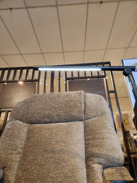 A close-up of the Venice PL447 Power Lift Chair by Golden with Twilight Tilt, under an LED lamp in a partitioned store.
