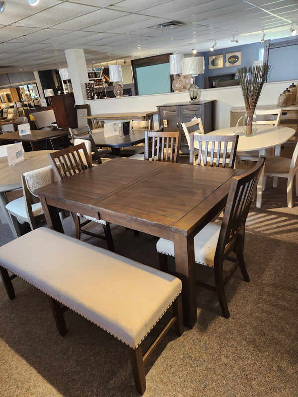 The Jofran Willow Creek Bench pairs with a wooden dining table and four chairs for a rustic showroom set.