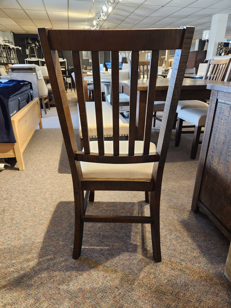 The Jofran Willow Creek Slatback Chair with upholstered seat is showcased in a modern furniture showroom.